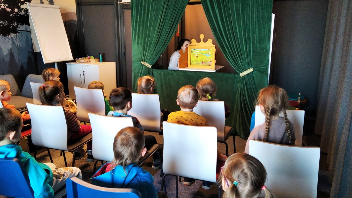 Pani bibliotekarka przedstawia dzieciom opowiadanie "Magiczna Gąsienica" w teatrzyku kamishiabi