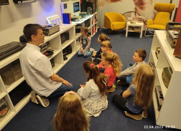 Grupa dzieci słucha prowadzącego warsztaty