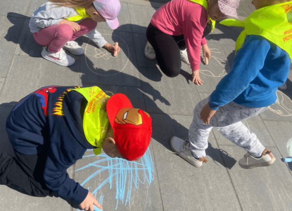 Dzieci rysują kredą na chodniku symbole związane z ekologią