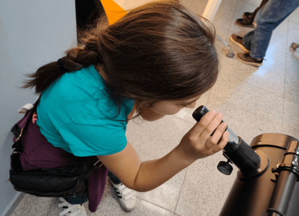 Dziewczynka patrzy przez teleskop
