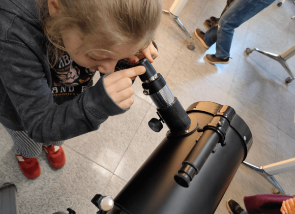Dziewczynka patrzy przez teleskop