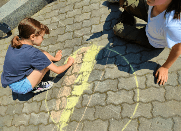 Dzieci rysują kredą na chodniku