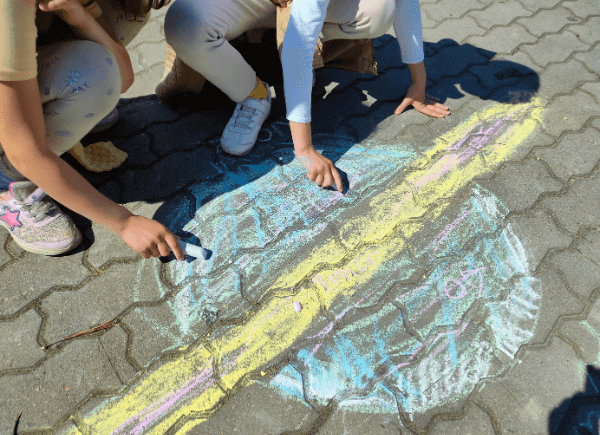 Dzieci rysują planetę na chodniku