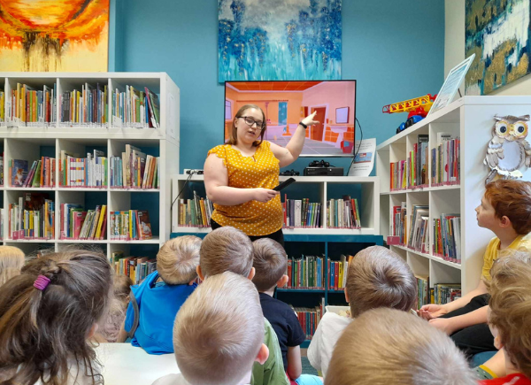 Zajęcia z przedszkolakami, bibliotekarka pokazuje na telewizor