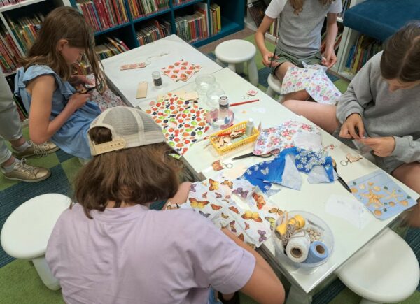 Zajęcia decoupage - na stole widać kolorowe serwetki, wokół stołu siedzą cztery dziewczynki