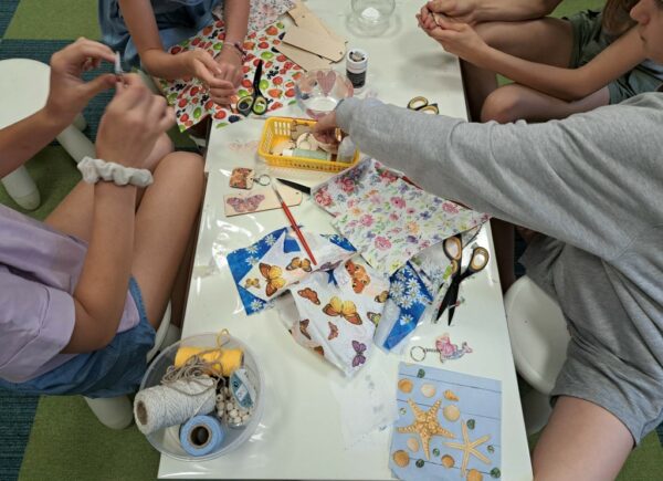 Zajęcia decoupage - na stole widać kolorowe serwetki, wokół stołu siedzą cztery dziewczynki