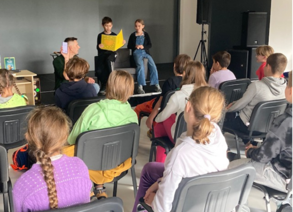 Dzieci czytają wiersz podczas spotkania autorskiego z Rafałem Witkiem