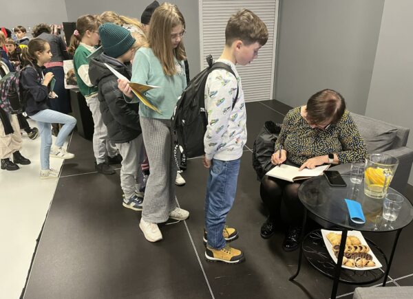 Uczniowie stojący w kolejce po autograf