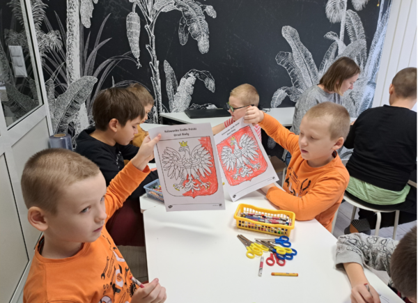 Dzieci pokazują kolorowanki z Godłem Polski
