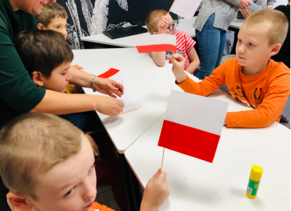 Dzieci prezentują wykonane na zajęciach papierowe flagi Polski
