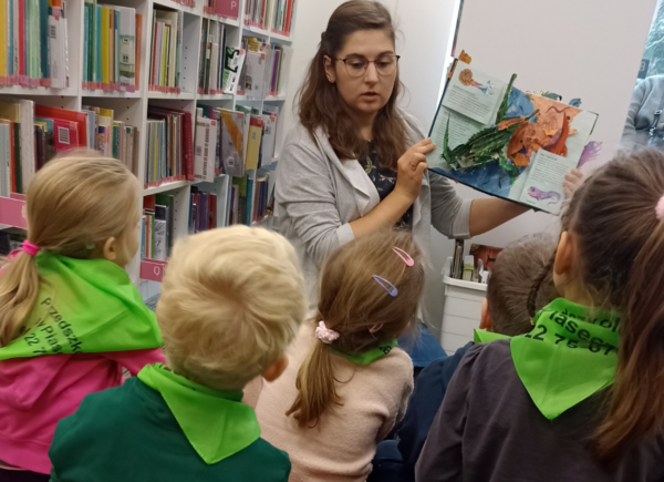 Dzieci oglądają prezentowane przez panią bibliotekarkę książki pop-upowe
