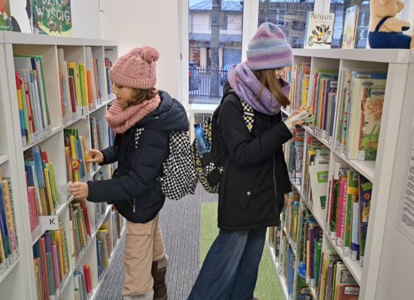Dziewczyny szukają papierowych bombek między książkami