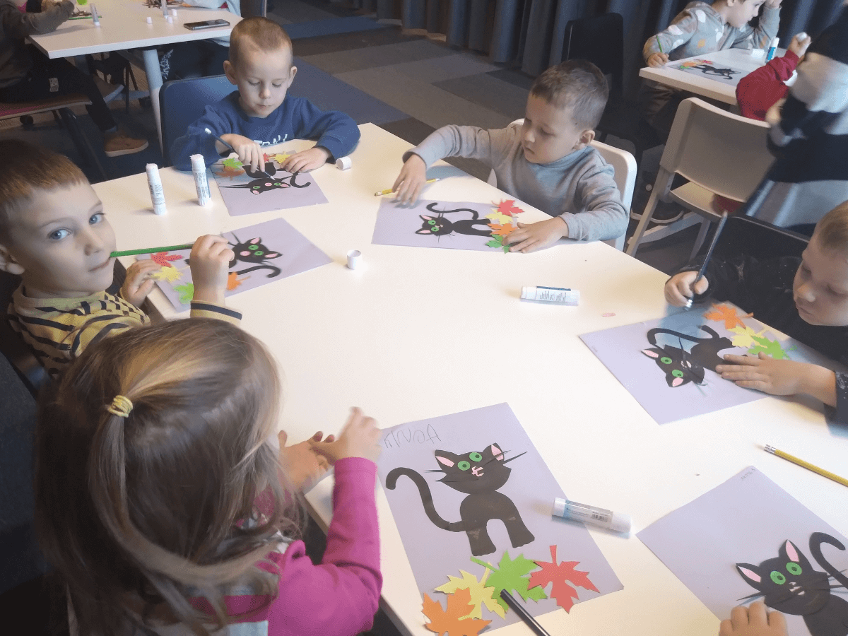 Dzieci wykonują papierowego czarnego kota