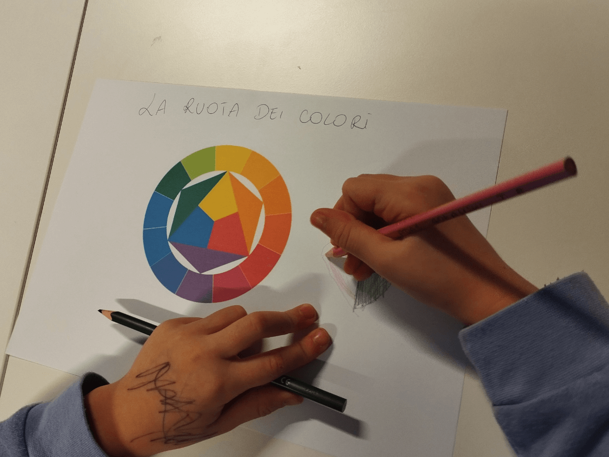 Dziecko rysuje serduszko obok koła kolorów.