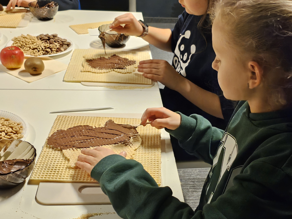 Uczestniczki warsztatów smarują czekoladą wzorów sów