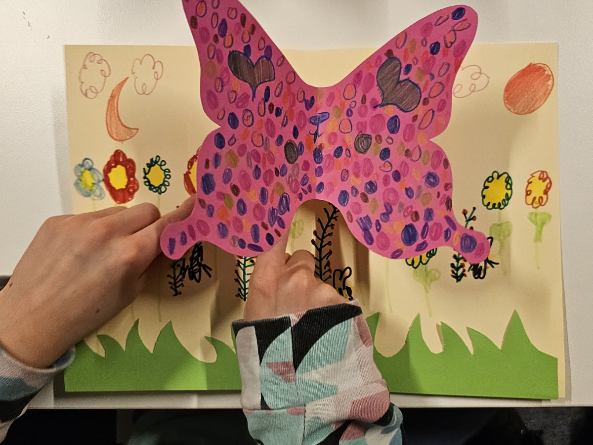 Dzieci wykonują kolorowe motyle wyskakujące przy otwieraniu złożonej kartki papieru