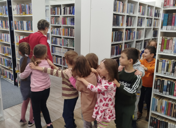Pani bibliotekarka oprowadza dzieci po bibliotece